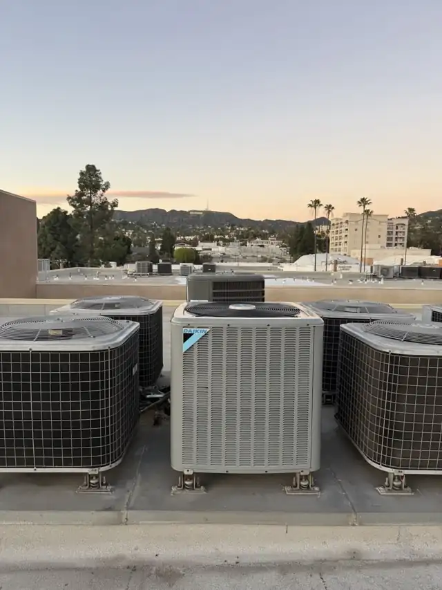 Rooftop AC condenser units including a Daikin unit overlooking Glendale and the Hollywood sign at sunset